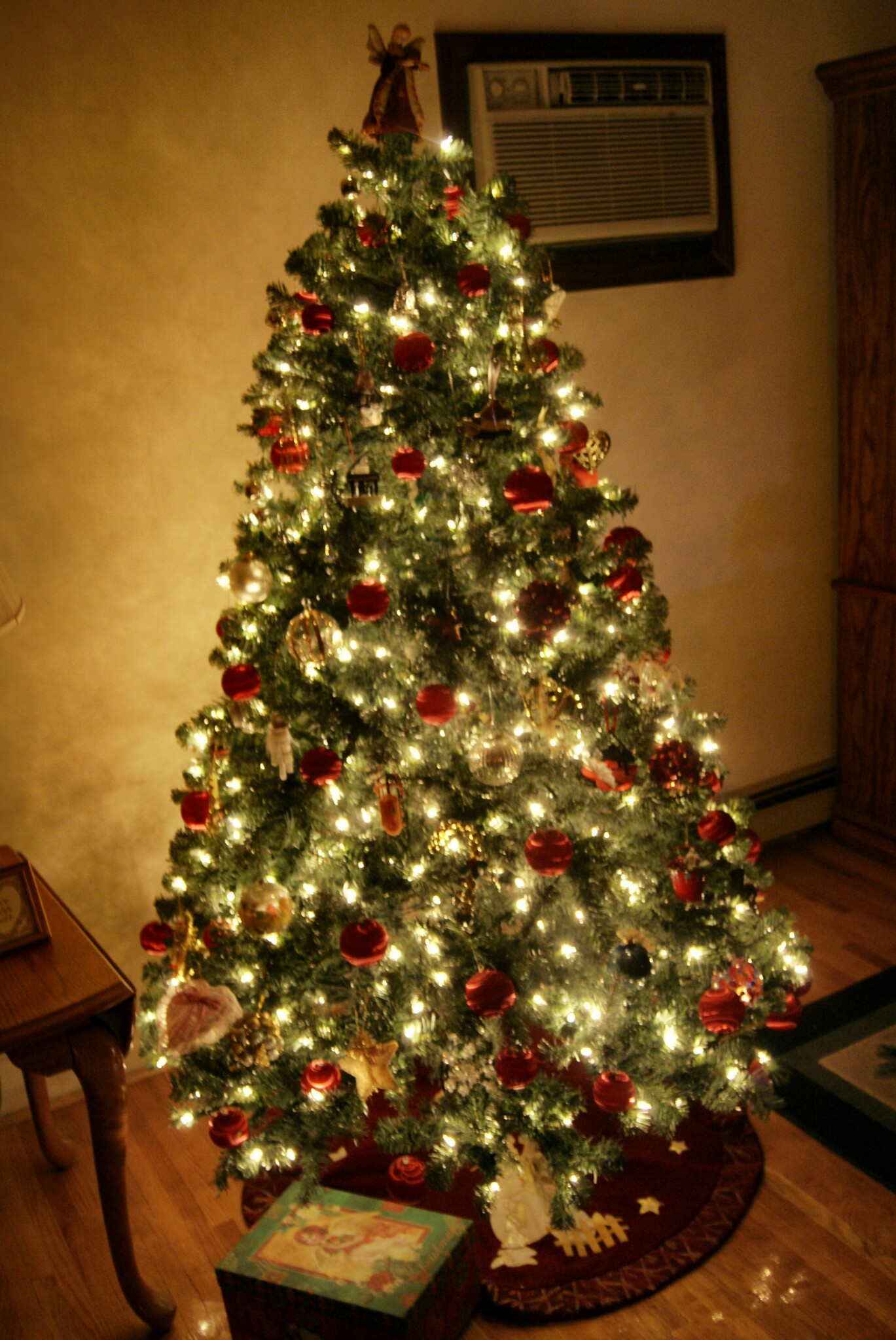 the lighted christmas tree is sitting in a corner