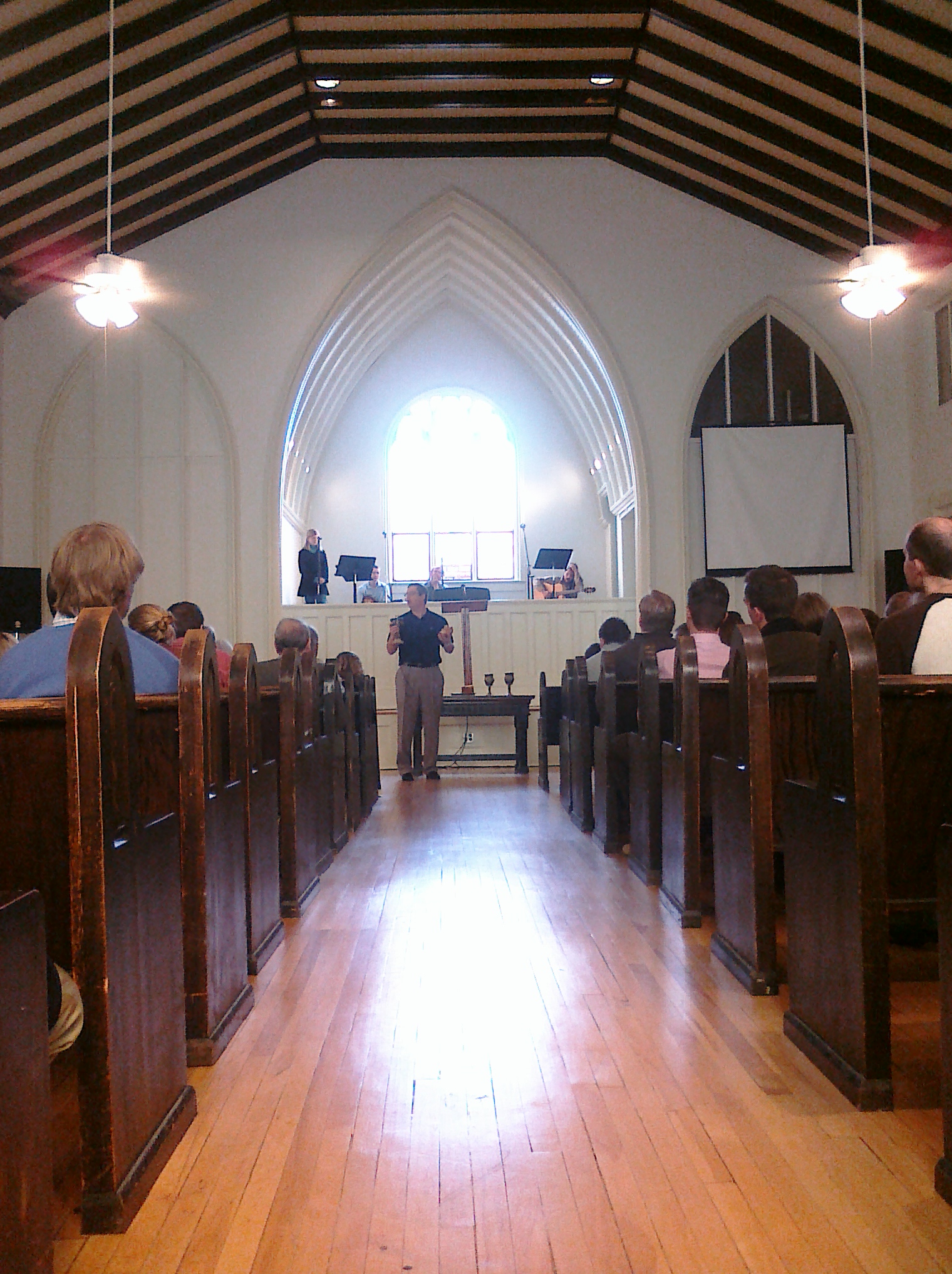 a church with people sitting in pews and standing on the other side