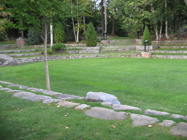 a large grassy area with stepping stone wall and green grass