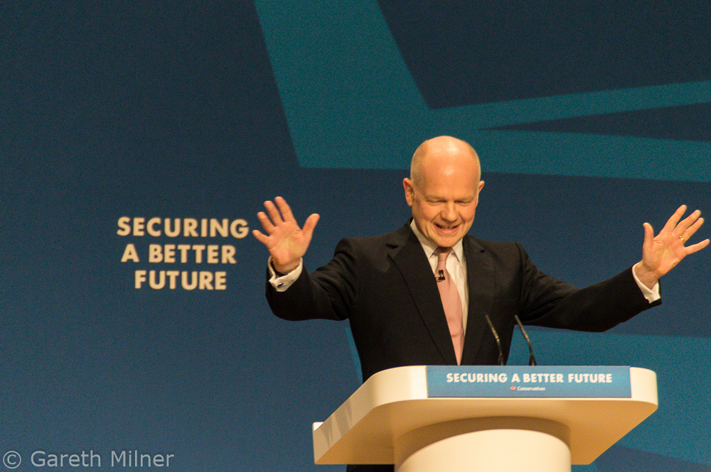 bald man speaking at podium with his hands open