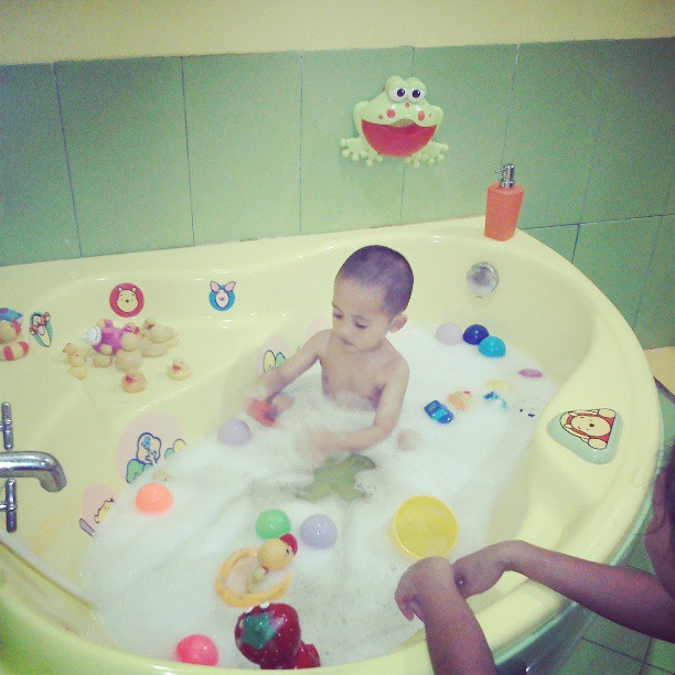 a baby sitting in a bathtub with toys