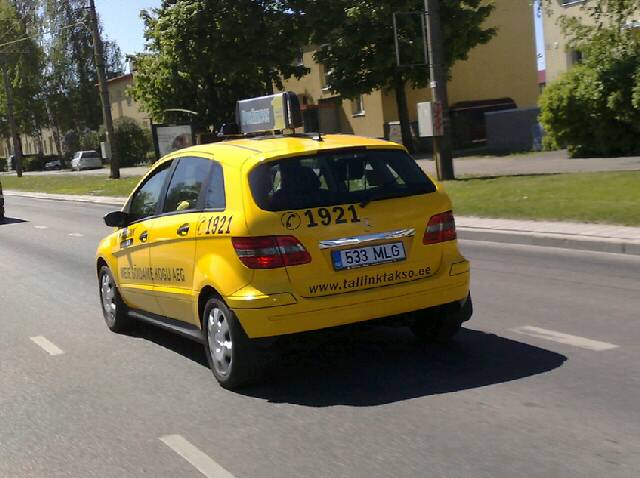 a taxi cab driving down the street on it's side