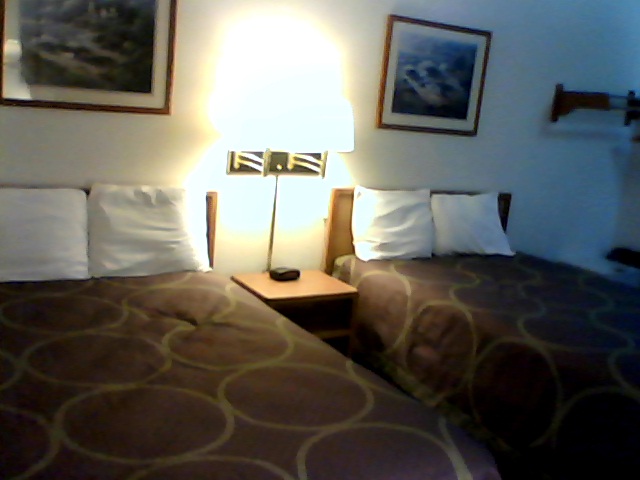 two beds in a el room with white sheets and brown bedding