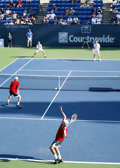 three people standing on top of a tennis court