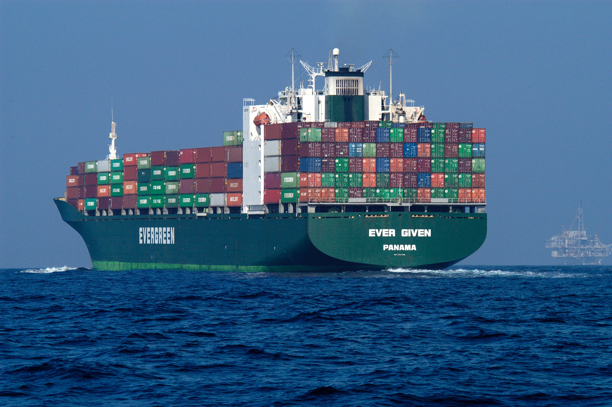 a large green and white cargo ship with lots of containers on top