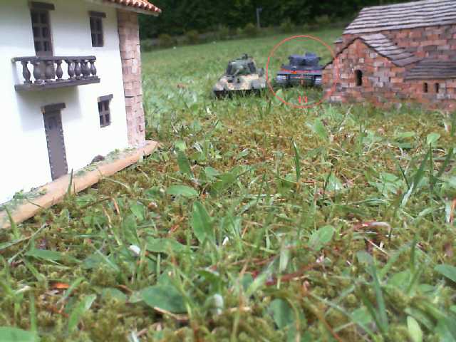 a small model house sitting in the middle of a grassy area