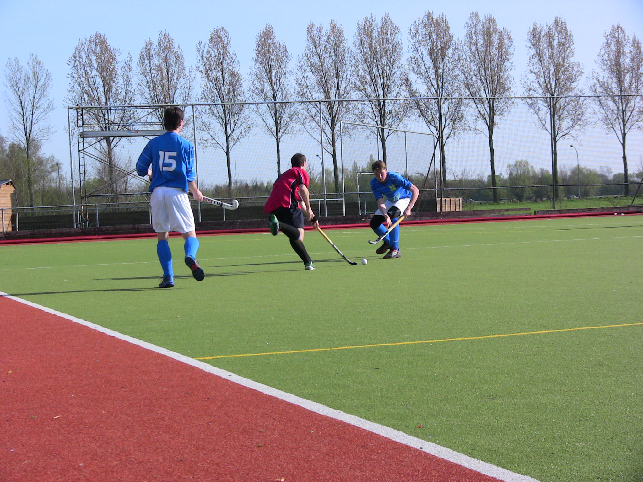 three men running and playing a game of hockey