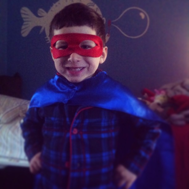 a little boy in a blue and red cape and mask