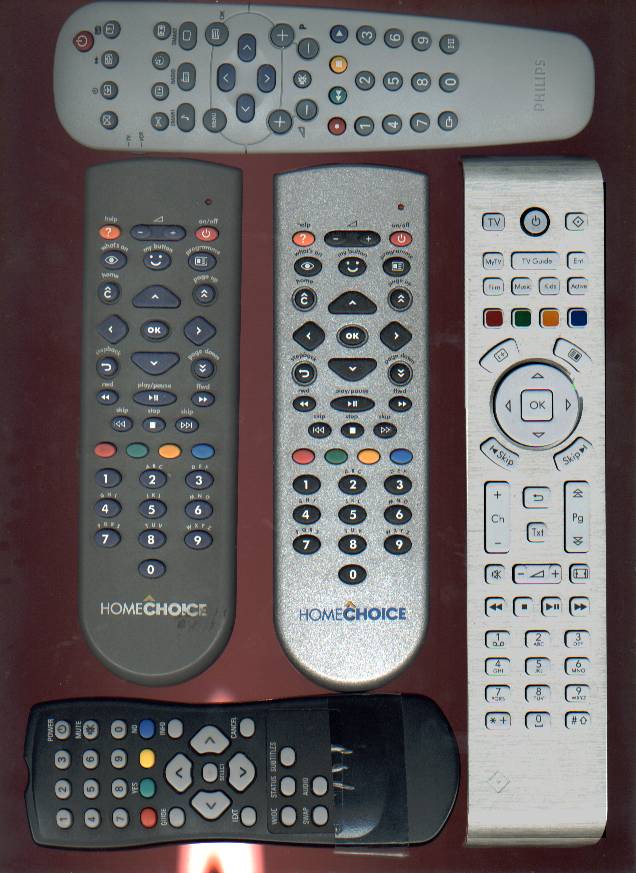 four remote controls lined up on a brown surface