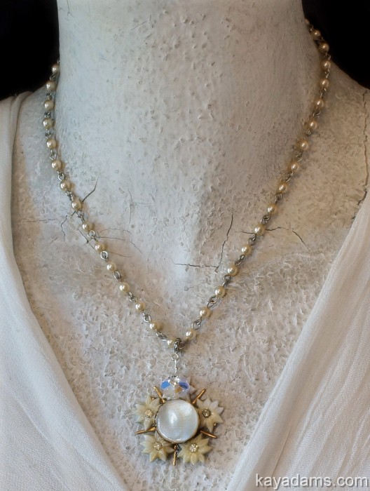 a beaded necklace on display next to an old white sweater