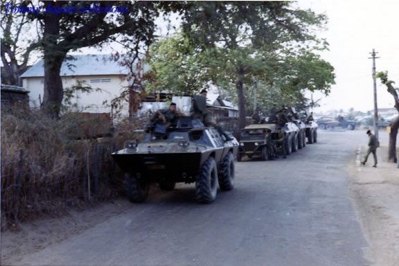 a street filled with armored vehicles next to trees