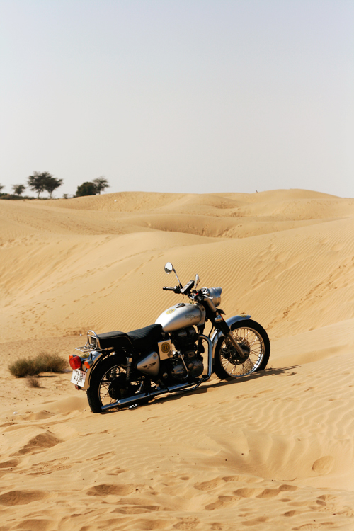 a motorcycle on sand dunes with trees in the background