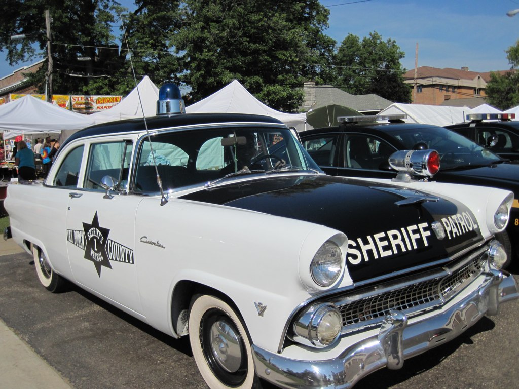 old school sheriff cars sitting next to tents