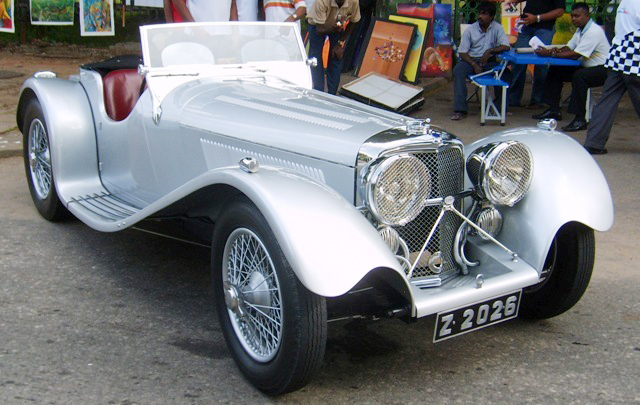 a vintage silver race car with a black and red stripe down the side