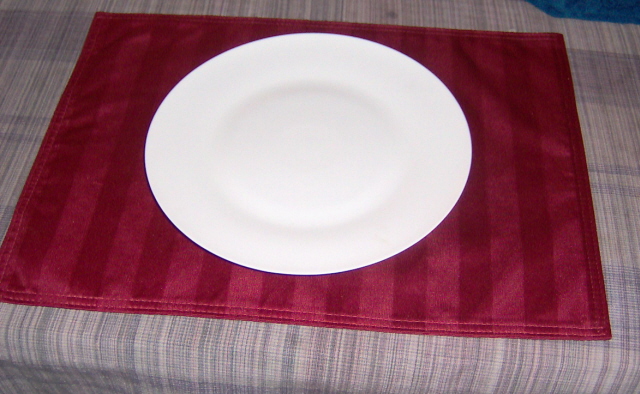 a plate and a red towel sit on the bed