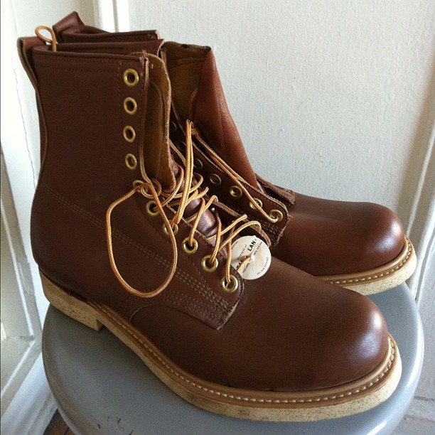a pair of leather brown boots with white label on them