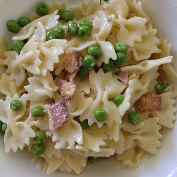 a white plate topped with pasta, peas and meat