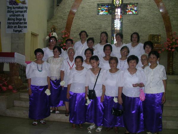 a group of women in white and purple outfits stand for a group po in a church