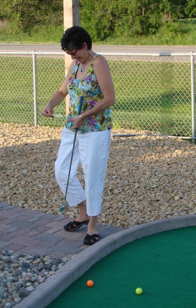 a woman about to put her golf ball in the hole