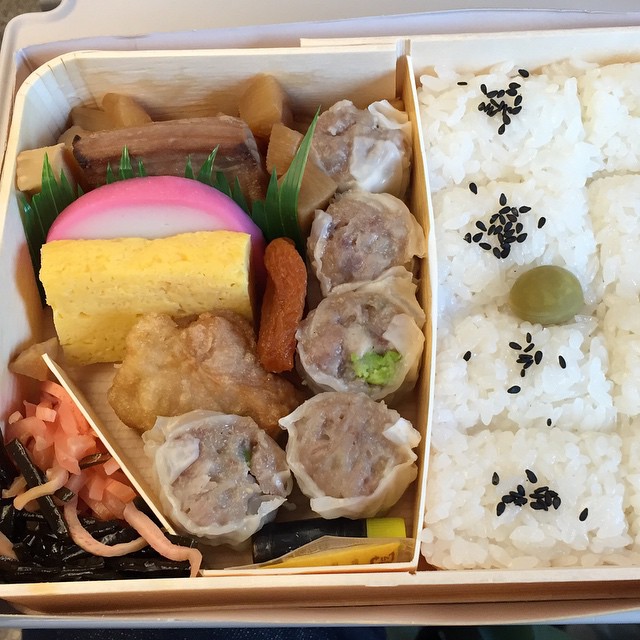a bento box contains rice, beans, meat, and fruits
