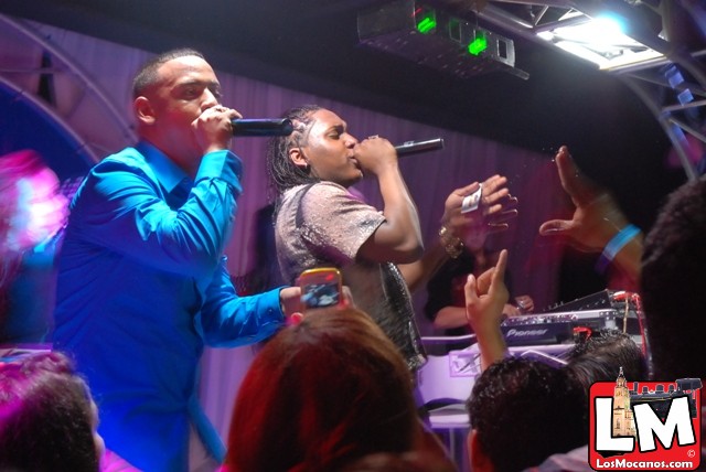 two people standing in front of a crowd on stage singing