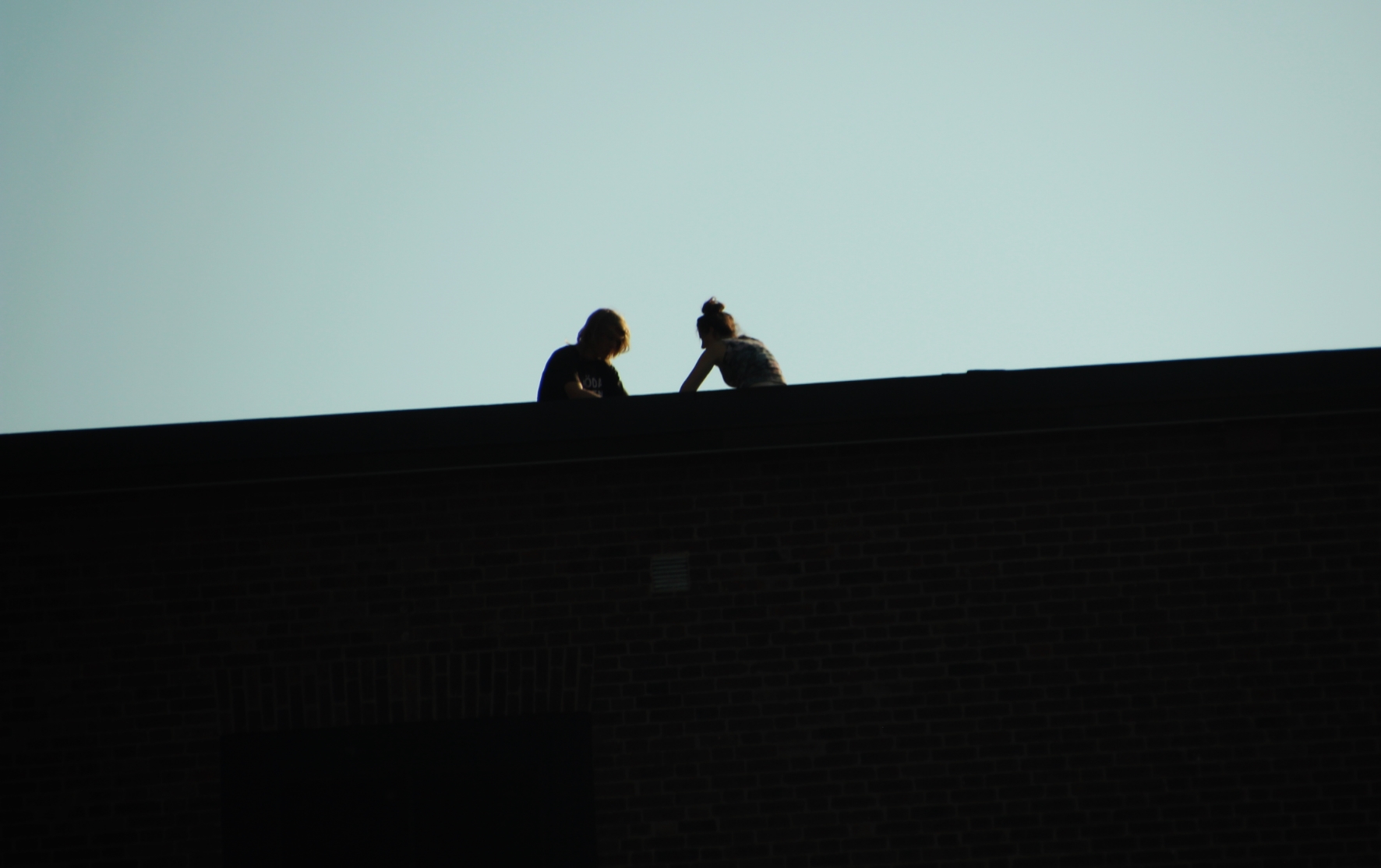 two people sitting on a roof in the dark