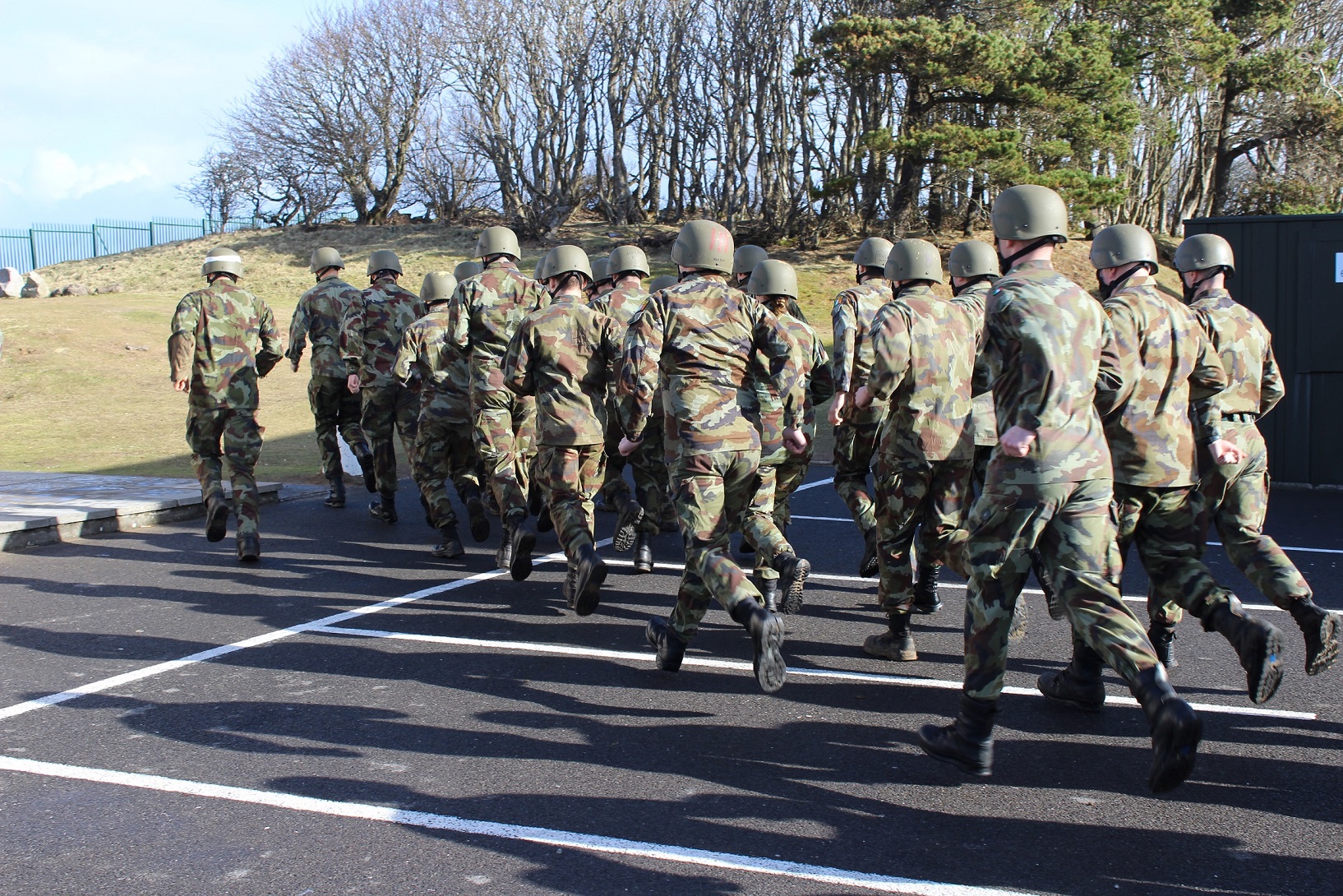 military personnel in full uniforms march down the road