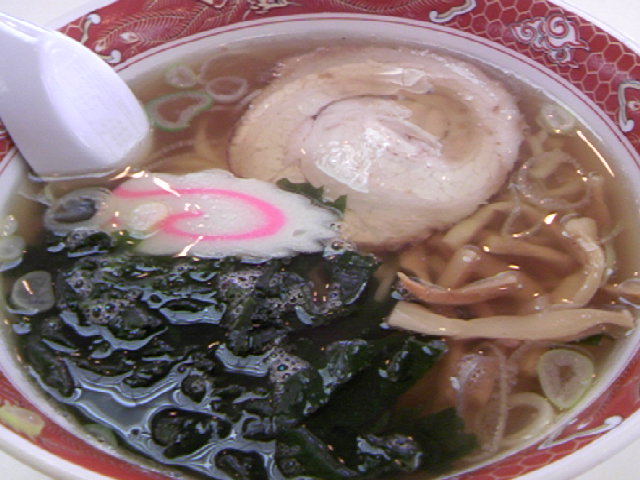 a white and red bowl with soup and noodles and spinach