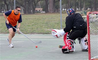 the ball comes to the net as the umpire and player wait on the field