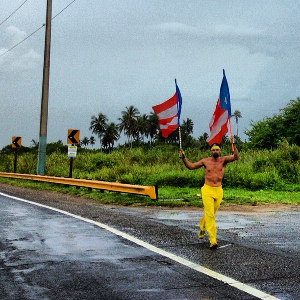 a man running down the street holding two american flags