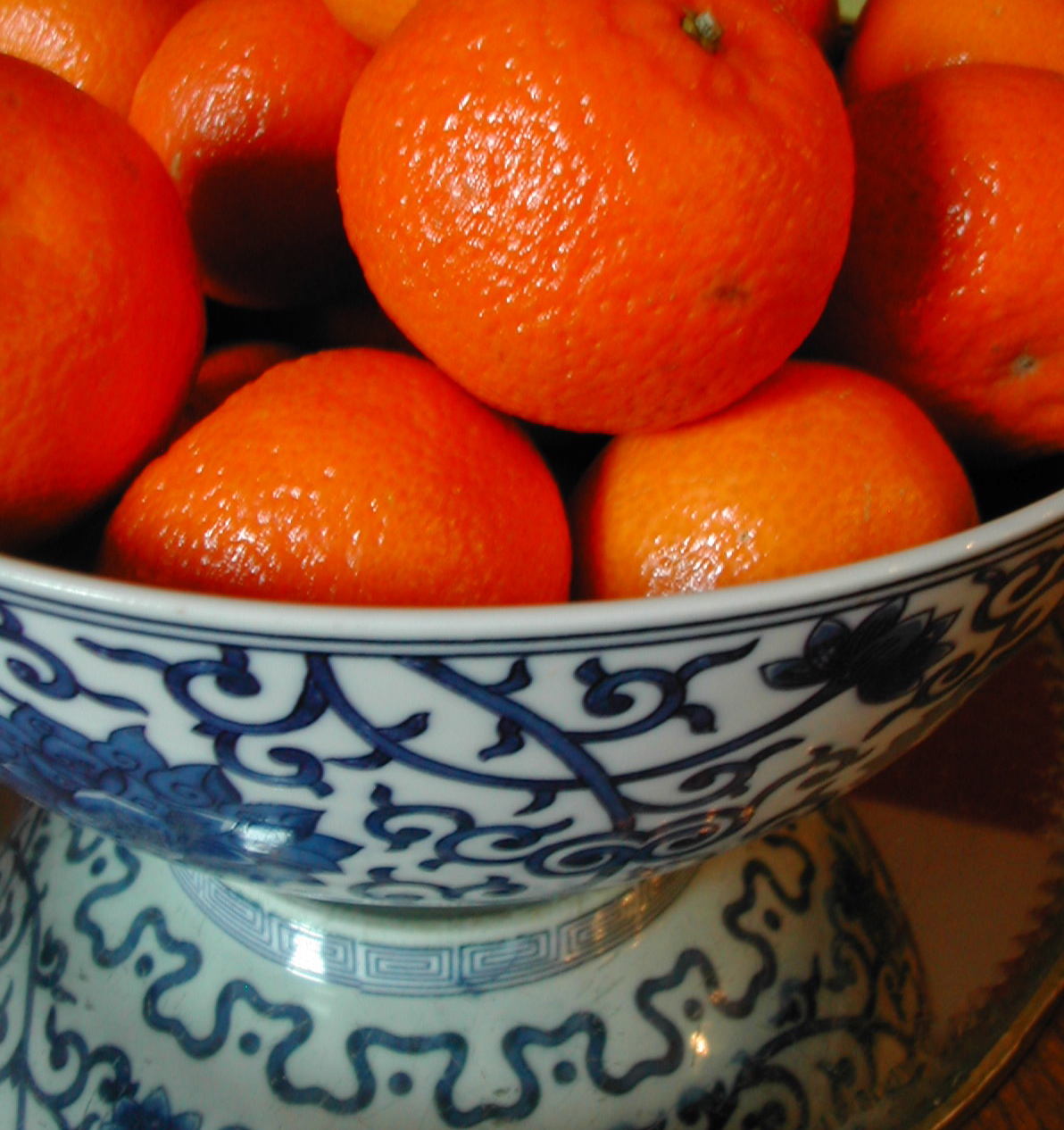 a blue and white bowl of oranges on a table