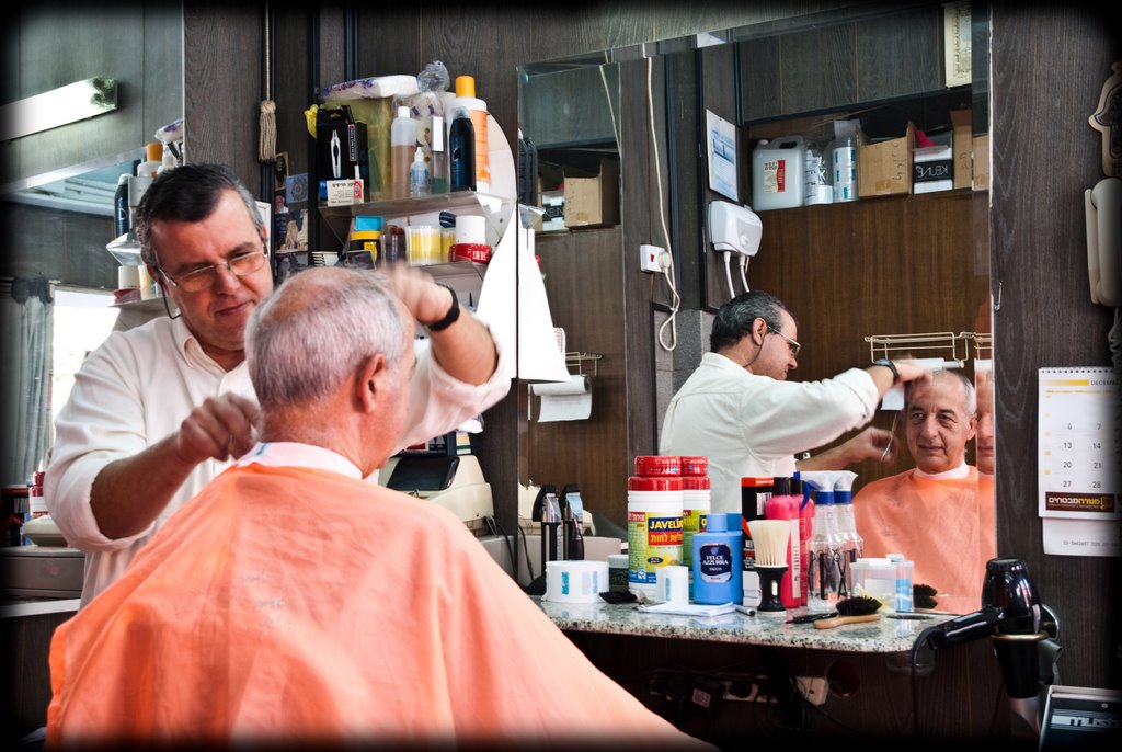 a man standing in front of a mirror while getting a hair cut
