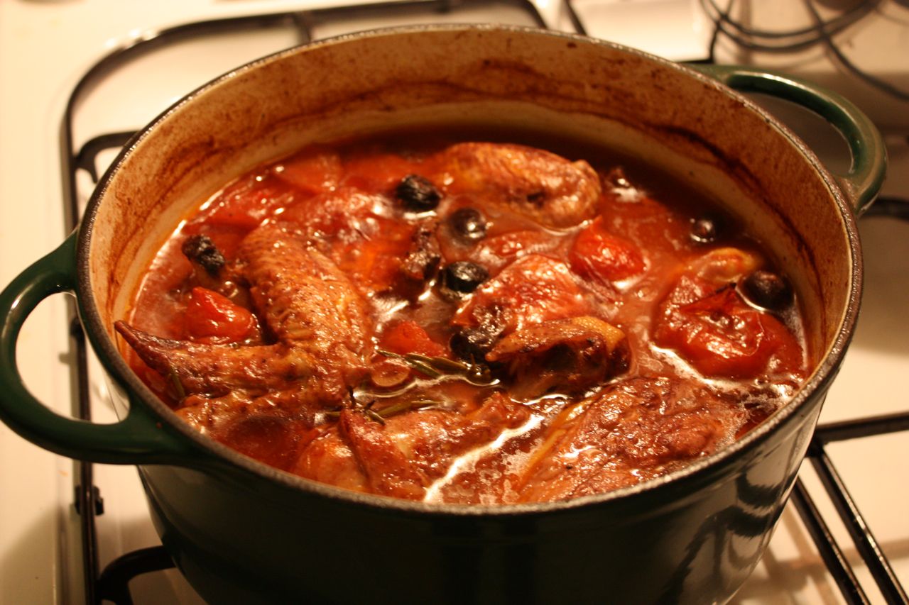 a large pot with meat, tomato sauce and olives