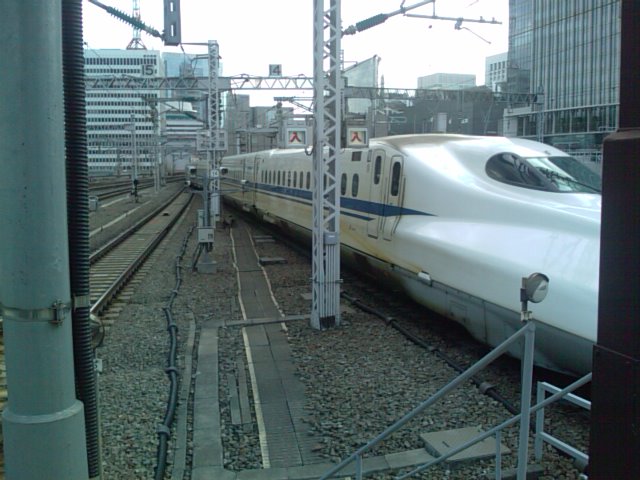 white train on the track going under the tower