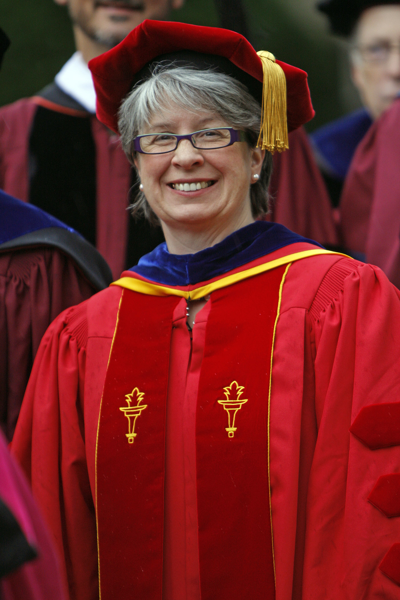 a woman is standing and smiling at graduation