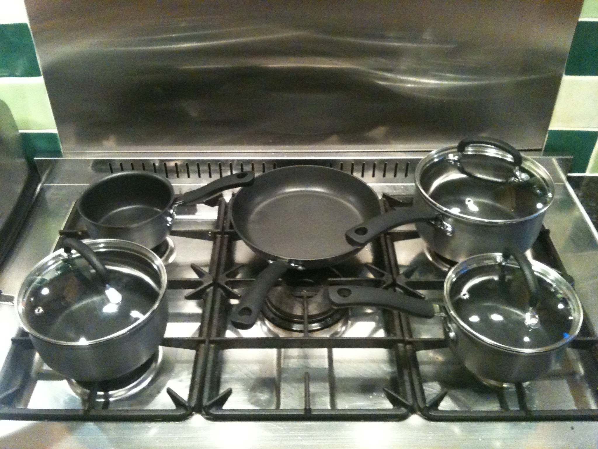 three saucepans sitting on top of the stove with one being filled
