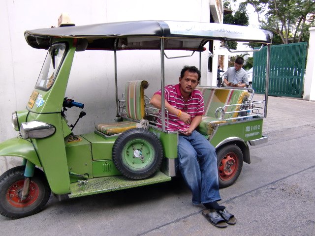 a man sitting on the seat of a cart with another person in it