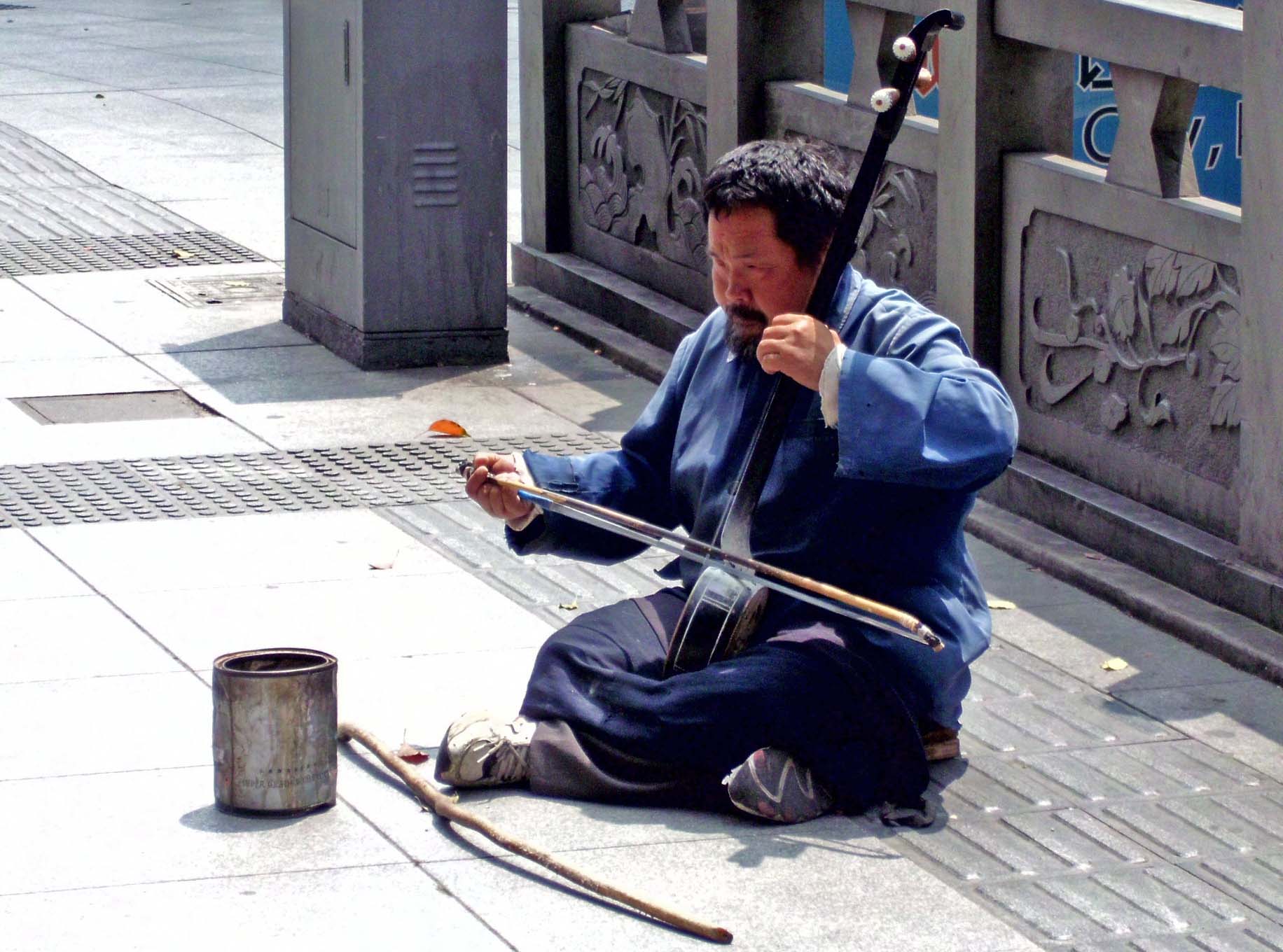 a man sitting on the ground with some sort of instrument in hand
