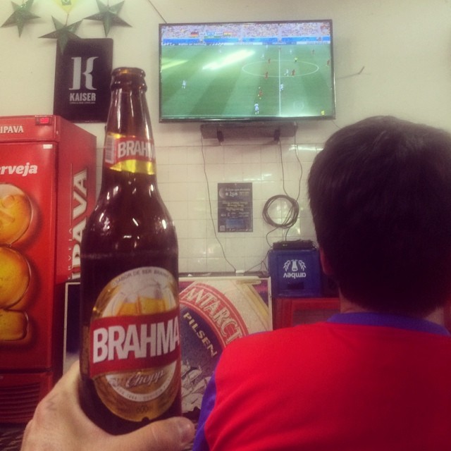 a man holding a beer bottle in front of a flat screen tv