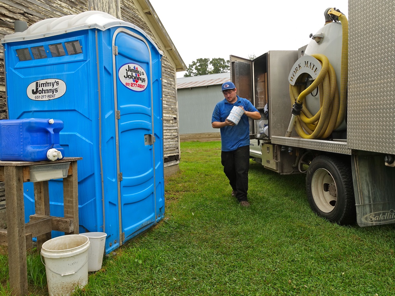 two men are standing by their portable toilets