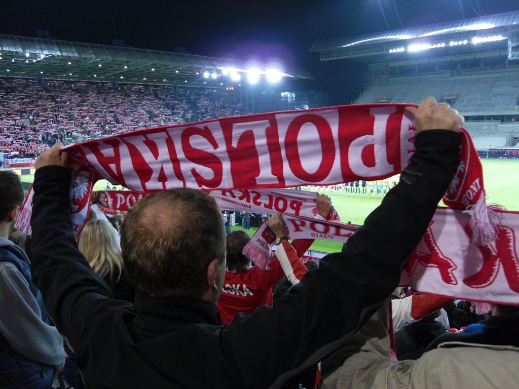 a crowd of fans holding red and white flags