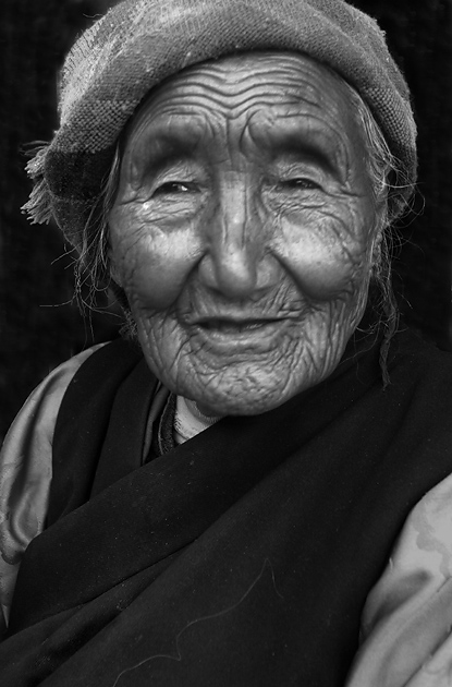 an elderly woman is wearing a straw hat and sitting