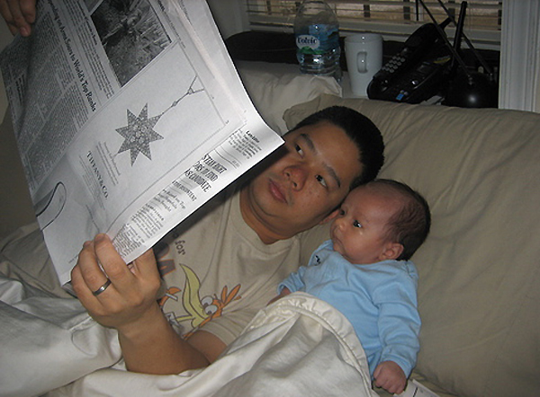 a man sitting on a couch reading to his child