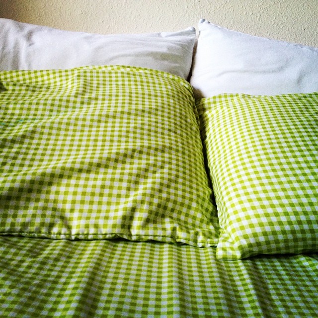 a green and white gingham bed spread with pillows