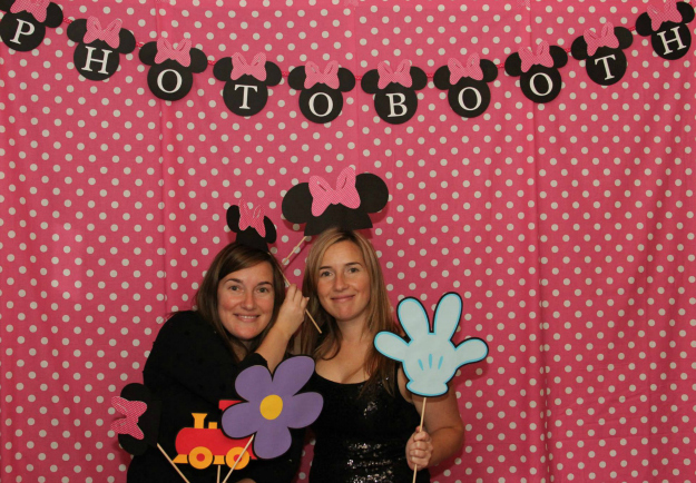 two woman posing in front of a po booth