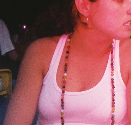 a woman in white shirt laying on floor with necklace