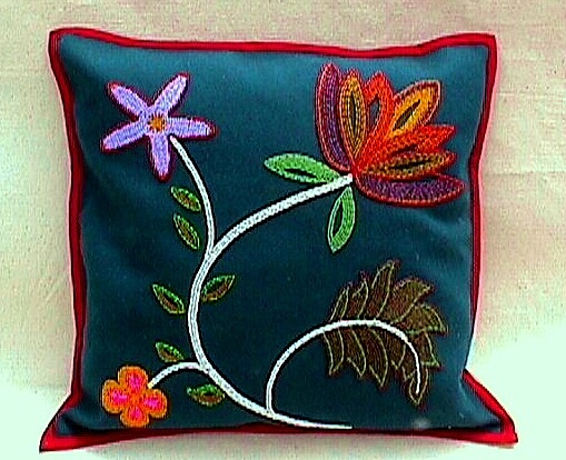 colorful embroidered flower on teal square pillow