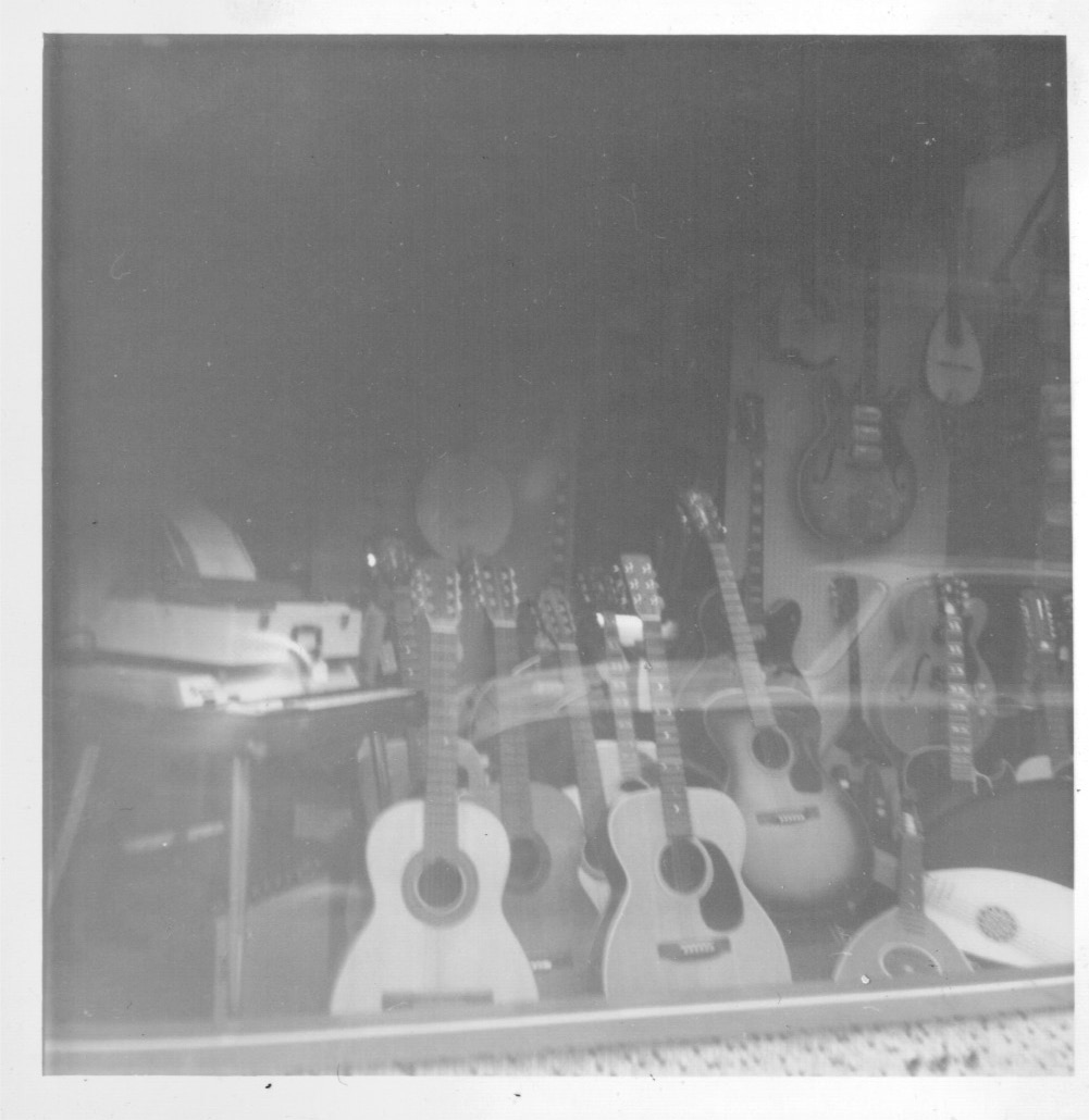 guitars are displayed behind glass of a shop window