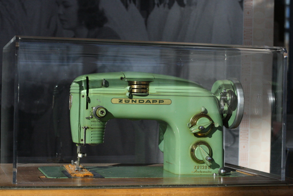 an old, green sewing machine inside a glass case