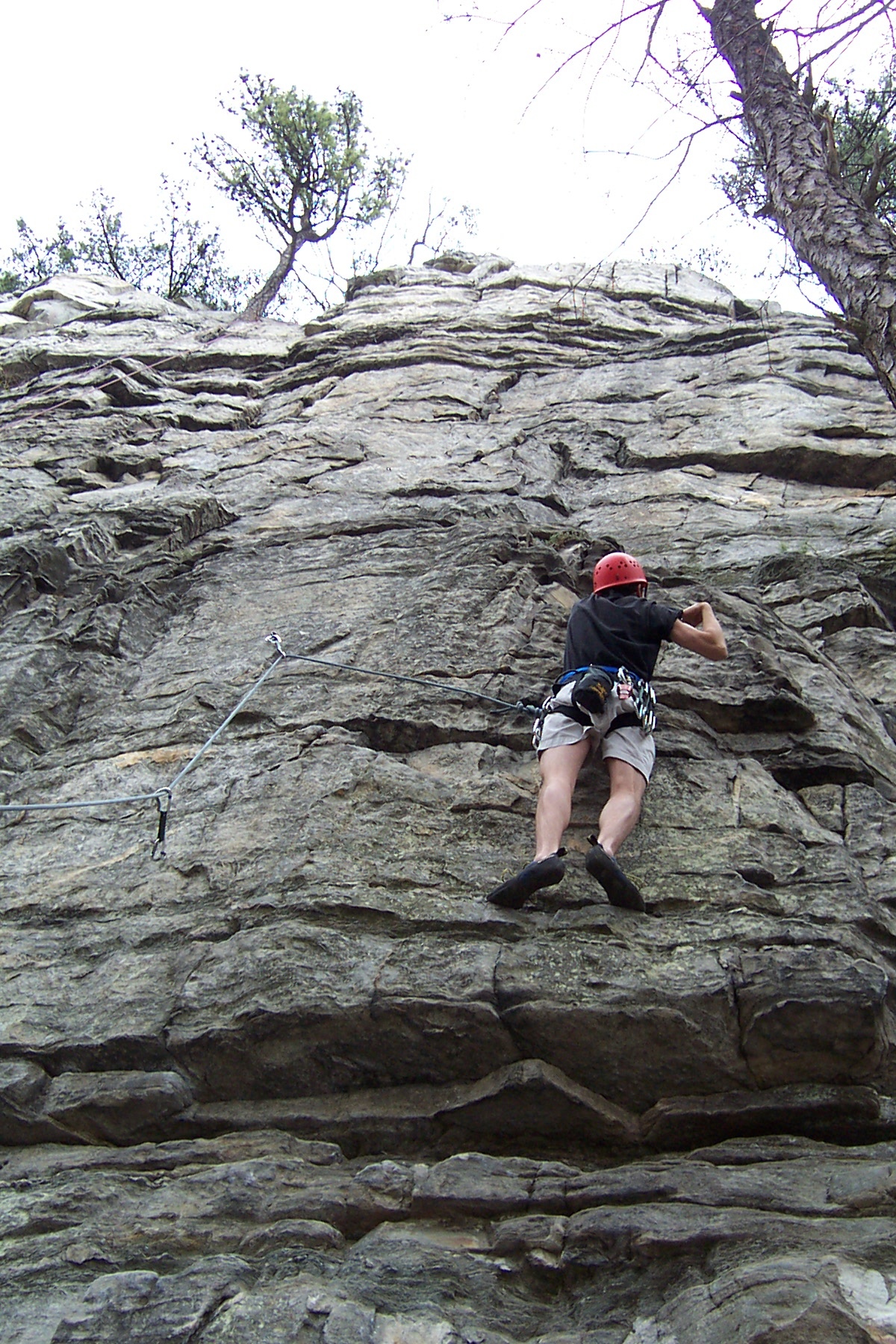 a man climbing up a rocky hill with trees around him